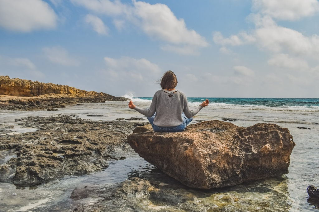 Femme au bord de la mer en position du lotus, elle bénéficie des bienfaits d'un moment de calme et de sérénité